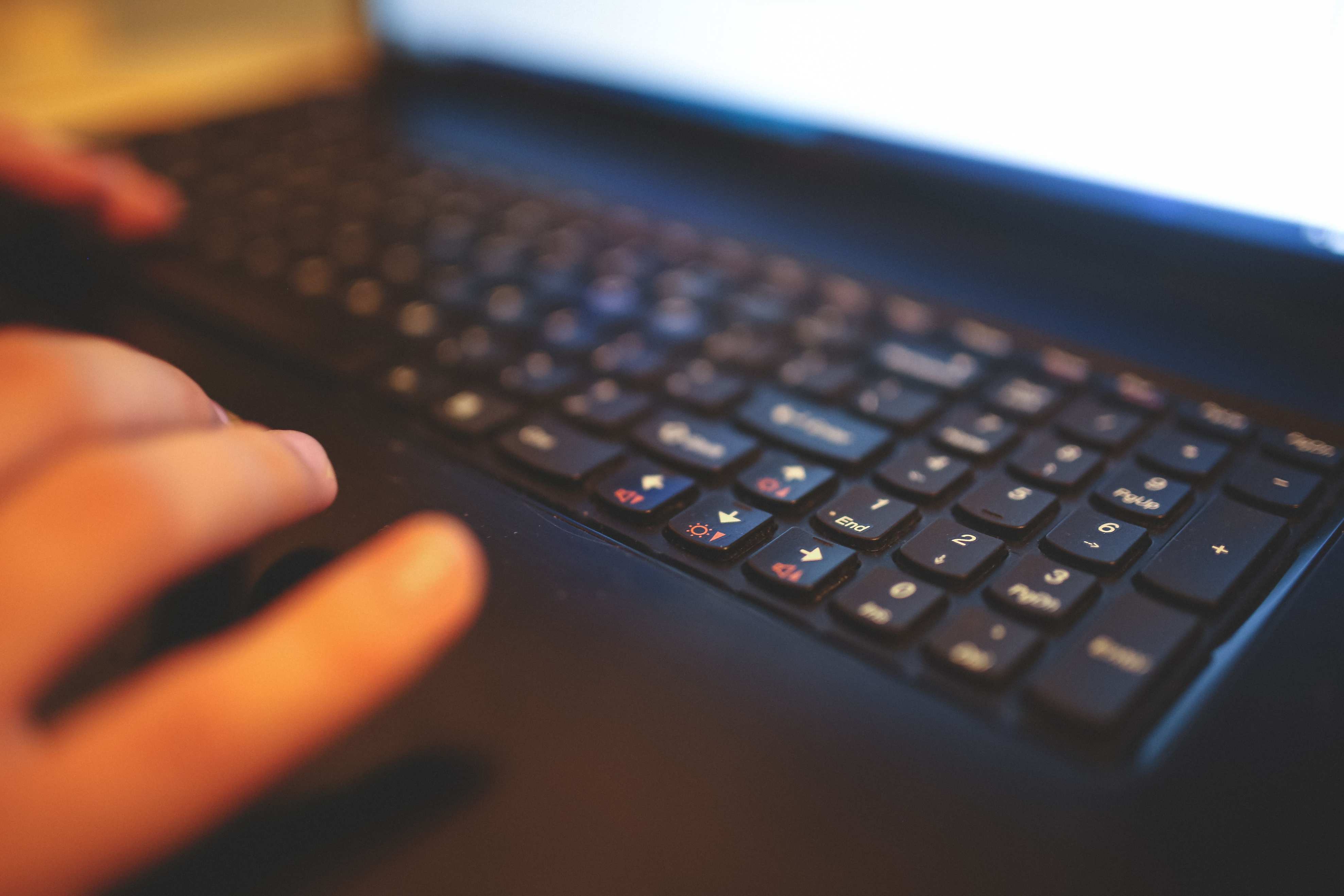 Developer hands on a laptop at a workstation, blurred close-up of hands typing on a keyboard