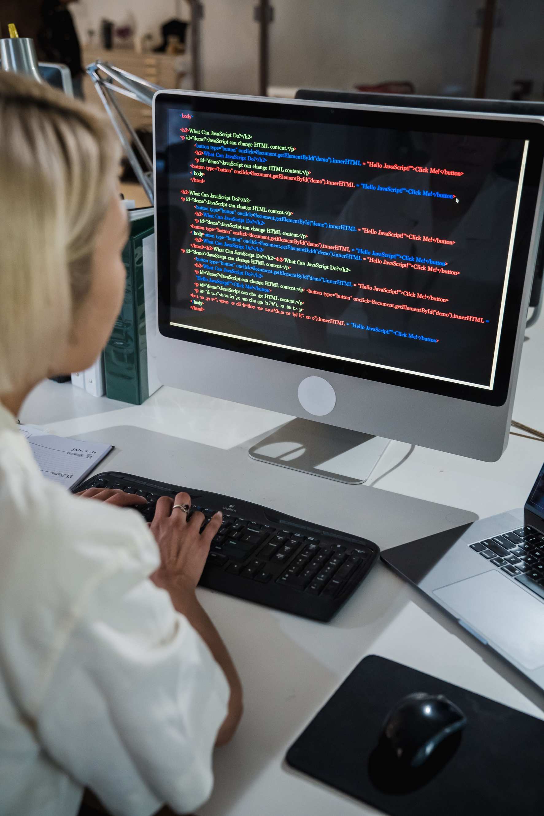 Close view of code on a display used for test automation, programmer working at a desktop in an office